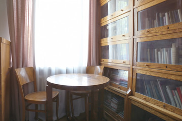 Wooden table and glass bookcase in room