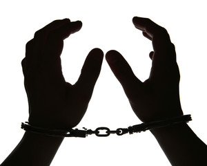 Black silhouette of man hands in handcuffs on light background