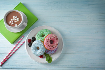 Plate with delicious donuts, berries and cup of coffee on white wooden table