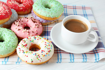 Delicious donuts and cup of coffee on napkin, closeup