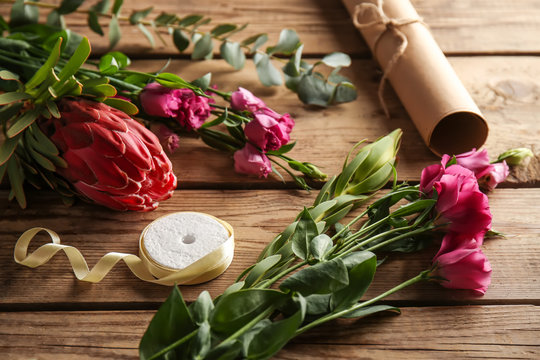 Beautiful flowers and packaging materials on wooden background