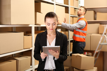 Young businesswoman with tablet at warehouse