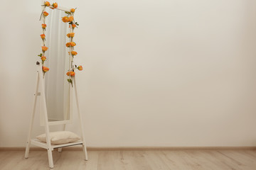 Mirror decorated with beautiful flowers near white wall