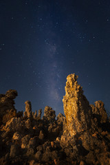 Tufa formation at Mono Lake at night with the Milky Way. Shallow depth of field with focus on lit prominent rock formation