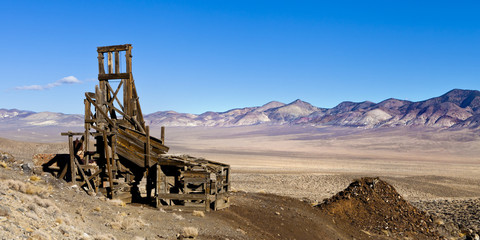 Old wooden mining hopper bin under blue sky in the Nevada Desert near a ghost town.