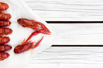 Red steamed crawfish on the white wooden background. Boiled crayfish. Rustic style. Seafood menu. Cover for the magazine.