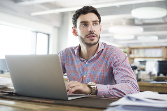 Thoughtful architect working on laptop in the office - Powered by Adobe