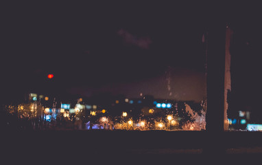 Frozen window with Blurred Defocused light of Night City, abstra