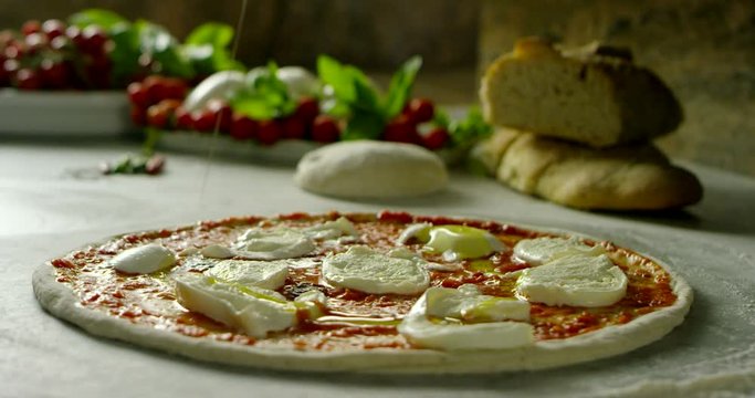 Super slow motion of a middle aged chef cutting mozzarella of bufala cheese for pizza on a restaurant kitchen table in 4k (close up)