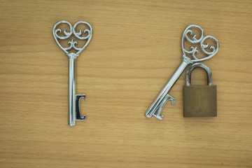 Key with a heart inside and lock on wood background