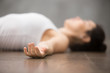 Beautiful young woman working out on wooden floor, resting after doing yoga exercises, lying in Shavasana Corpse or Dead Body Posture , relaxing. Close up, focus on hand