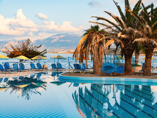 Nice view on the swimming pool with palm trees on the shore of the Mediterranean Sea in Greece. Crete