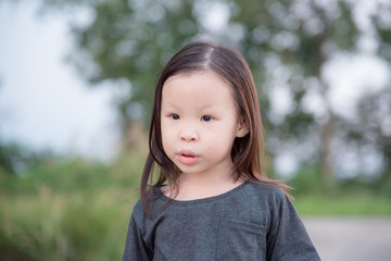 Little asian girl standing in park and looking something