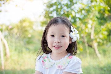 Little asian girl with flower on hair in garden
