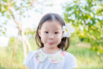 .Little asian girl with flower on hair in garden