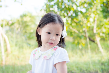 .Little asian girl with flower on hair in garden
