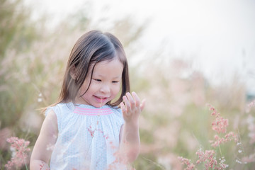 Little asian girl playing with wild flower in field