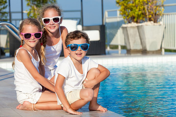 Three happy children playing on the swimming pool at the day tim