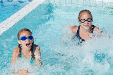 Naklejka premium Two happy children playing on the swimming pool at the day time.