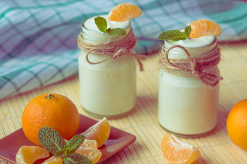 Fresh organig natural white yogurt in glass jars with tangerine