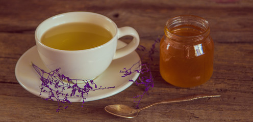 Cup of tea with honey in jar on the wooden table