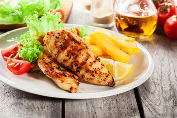 Grilled chicken breasts served with fries and fresh salad