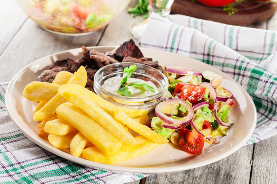 Grilled meat with French fries and fresh vegetables