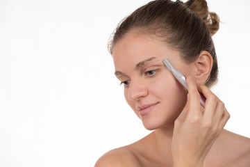 Young girl in a red towel caring for your eyebrows with trimmer