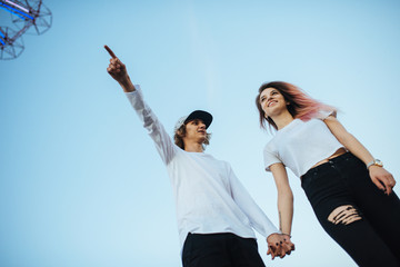 Young hipster boy pointing finger to the sky to show something to his girlfriend