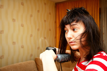 Girl dries hair and makes the hairstyle in her room. She uses the Hairdryer and comb. The home interior 2