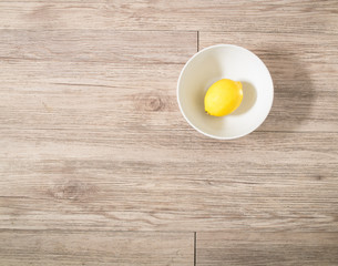Top view - Fresh lemon in a white bowl on wooden background ( Space and composition for text )