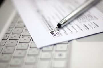 Tax Season: 1040 U.S. Individual Income Tax Return Form horizontal top view with an office laptop and blue calculator as background together with a red white pen preparation on taxation as foreground