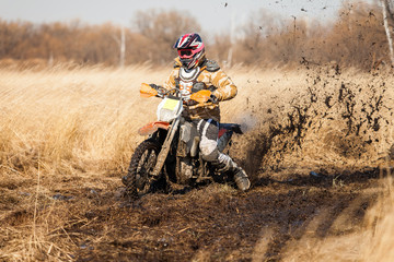 Enduro bike rider on a field with dry grass in autumn. The motor