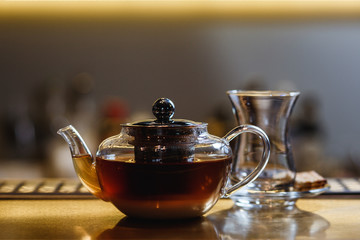 An underexposed lifestyle horizontal image of a teapot with hot alcoholic cocktail on a black tea...