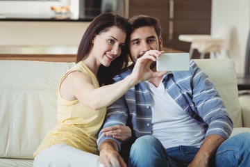 Romantic couple relaxing on sofa and taking a selfie
