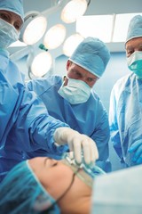 Surgeons adjusting oxygen mask on patient 