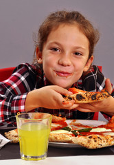 niña contenta comiendo pizza y bebiendo gaseosa.