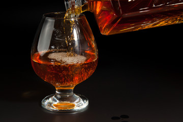 Cognac is poured from a bottle into  glass