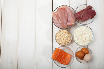 Proteins, fish, cheese, eggs, meat and chicken on a white wooden background