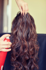 stylist with hair spray making hairdo at salon