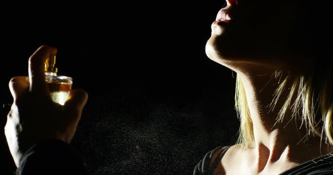 anonymous woman spraying fragrance in extreme slow motion, with scent particles to wet skin after showering.