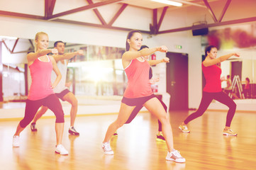 Obraz premium group of smiling people exercising in the gym