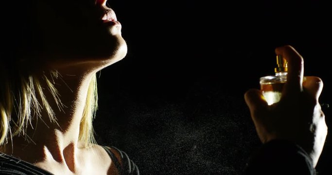 anonymous woman spraying fragrance in extreme slow motion, with scent particles to wet skin after showering.