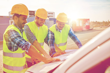 close up of builders with blueprint on car hood