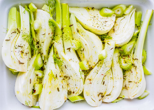 Sliced fresh fennel bulbs with herbs and spices ready for cooking.
