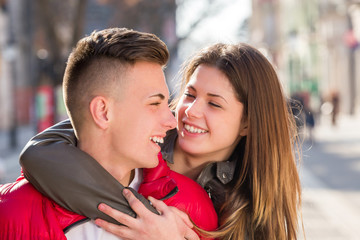 young teen couple having piggyback carrying on walking street in