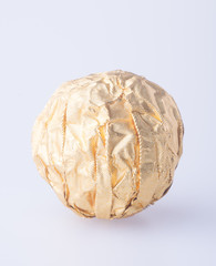 Chocolate ball in a gold foil paper on a background.