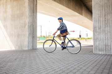 young hipster man with bag riding fixed gear bike