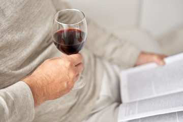 close up of senior man with wine glass and book