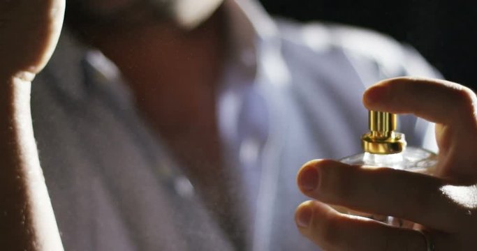 anonymous man spraying fragrance in extreme slow motion, with scent particles to wet skin after showering.